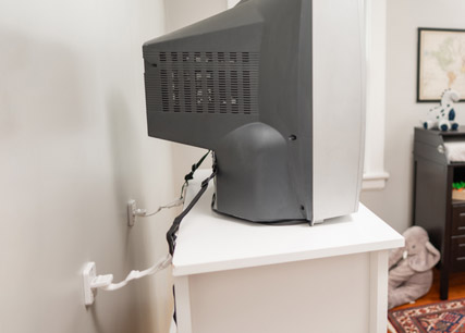 CRT TV attached to wall with two brackets and straps